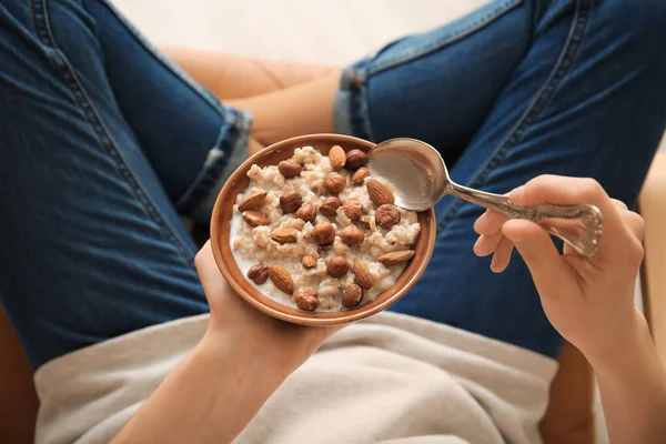 Ung kvinna äter god söt havregrynsgröt hemma — Stockfoto