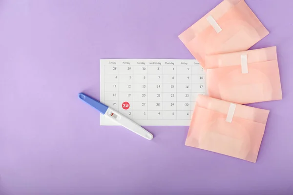 Negative pregnancy test, calendar and menstrual pads on color background — Stock Photo, Image