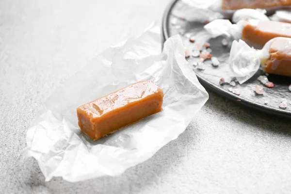 Tasty salty caramel candy on grey table — Stock Photo, Image