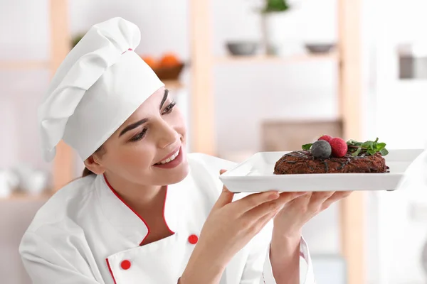 Young female confectioner with tasty dessert in kitchen Stock Image