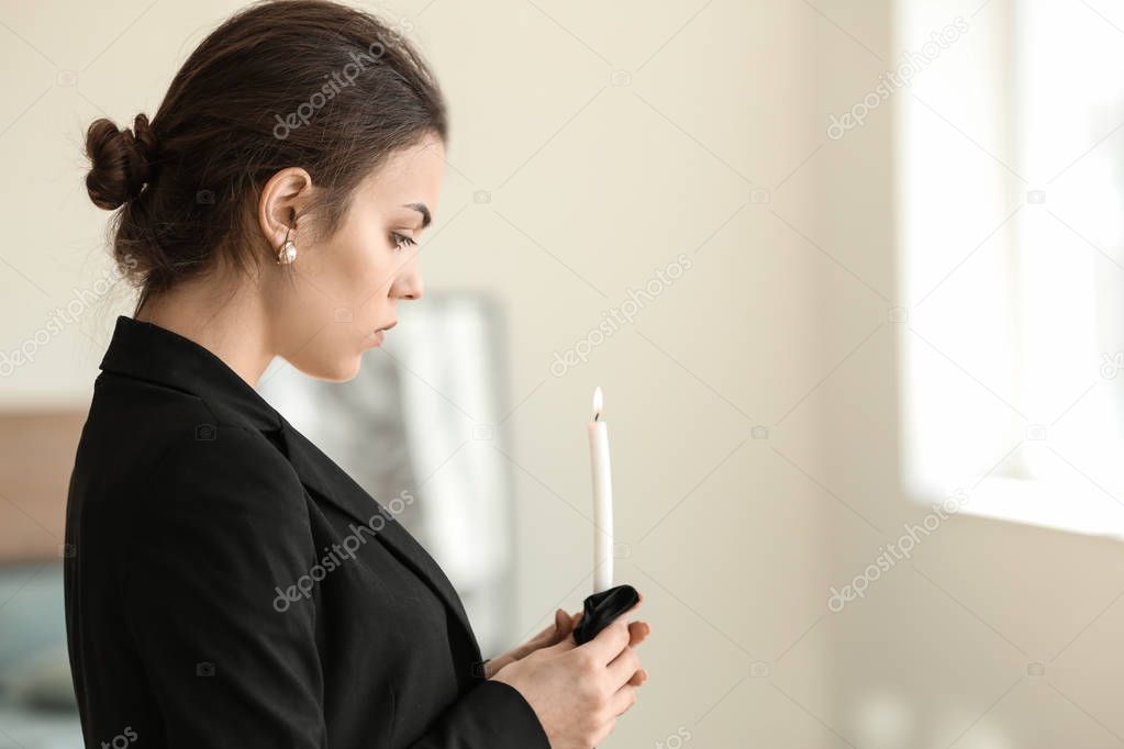 Woman with candle pining after her relative at funeral