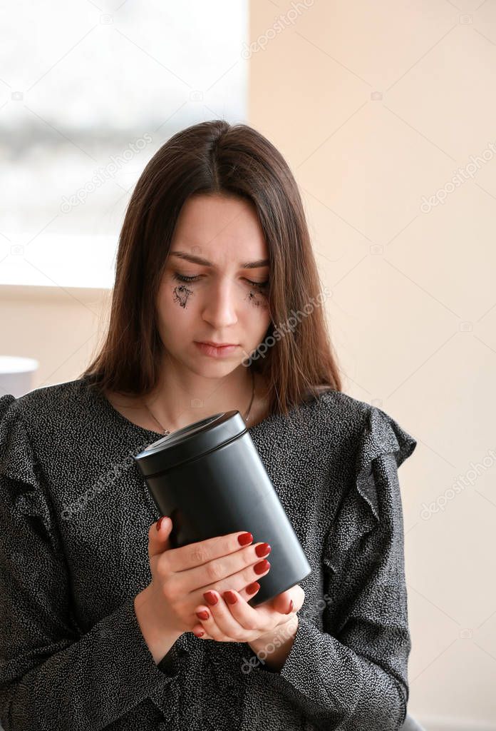 Sad woman with mortuary urn at funeral