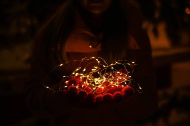 Karanlıkta parlayan Noel ışıkları ile Kadın eller