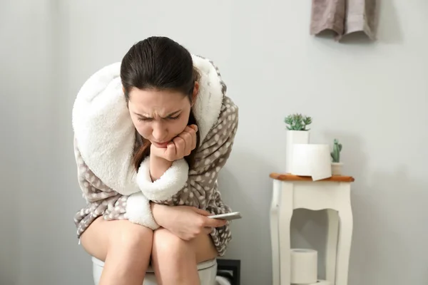 Young woman suffering from constipation on toilet bowl at home — Stock Photo, Image