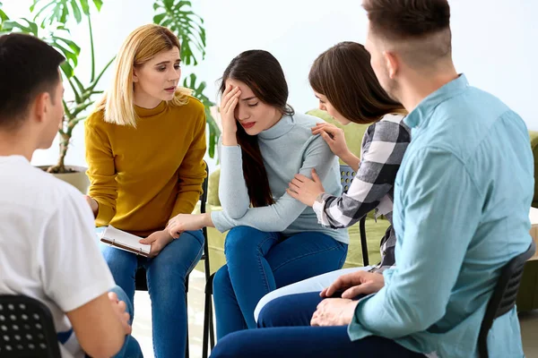 People calming woman at group therapy session