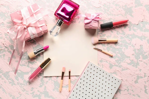 Empty sheet of paper with gift boxes and makeup cosmetics on color background