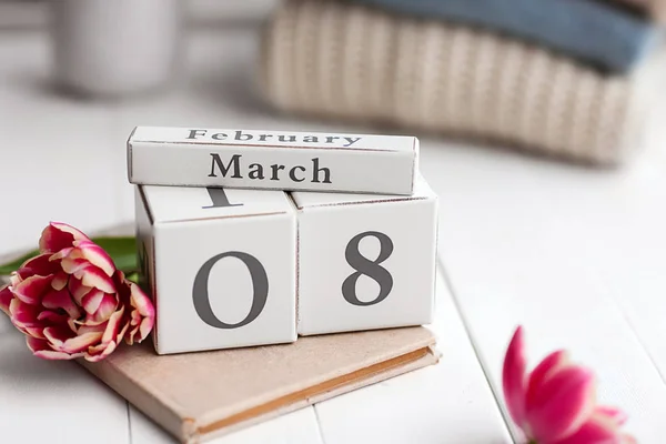 Kalender med datum 8 mars, bok och blomma på vitt bord — Stockfoto