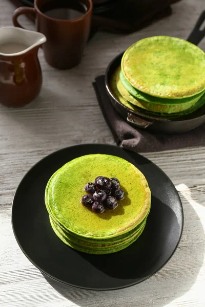 Тарелка с вкусными зелеными блинчиками на столе — стоковое фото