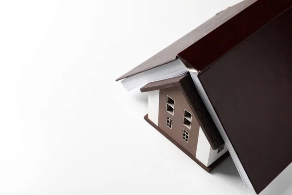 Modelo de casa con libro sobre fondo blanco. Concepto de terremoto —  Fotos de Stock