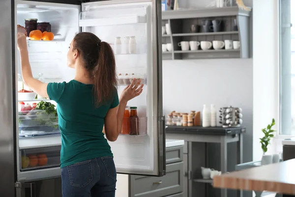 Mujer sacando comida de la nevera en casa —  Fotos de Stock