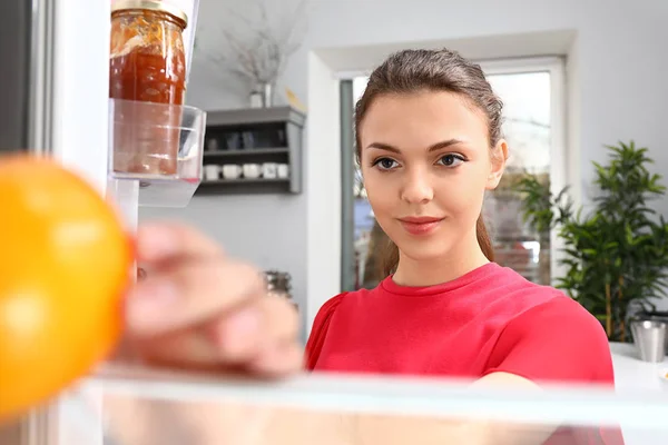 Frau holt zu Hause Lebensmittel aus dem Kühlschrank, Blick von innen — Stockfoto