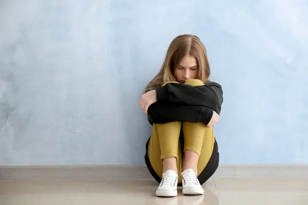 Sad teenage girl near color wall — Stock Photo, Image