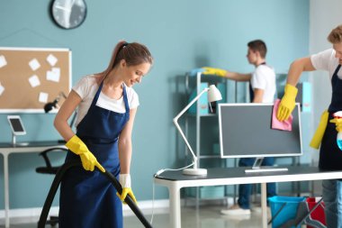 Ofiste elektrikli süpürge ile kadın hademe