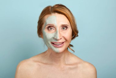 Renkli arka plan karşı yüzünün yarısında maske ile Olgun kadın