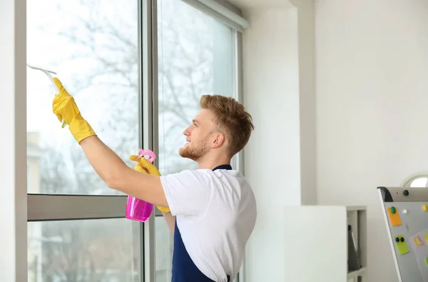 Hausmeister putzt Fenster im Büro — Stockfoto