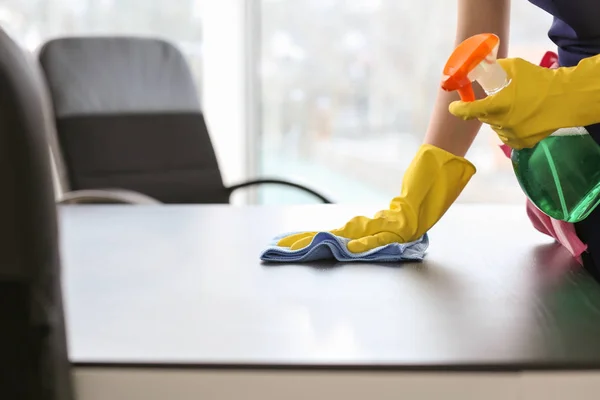 Vrouwelijke janitor schoonmaak tafel in Office — Stockfoto
