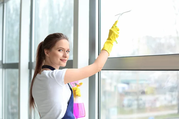 Petugas kebersihan wanita membersihkan jendela di kantor — Stok Foto