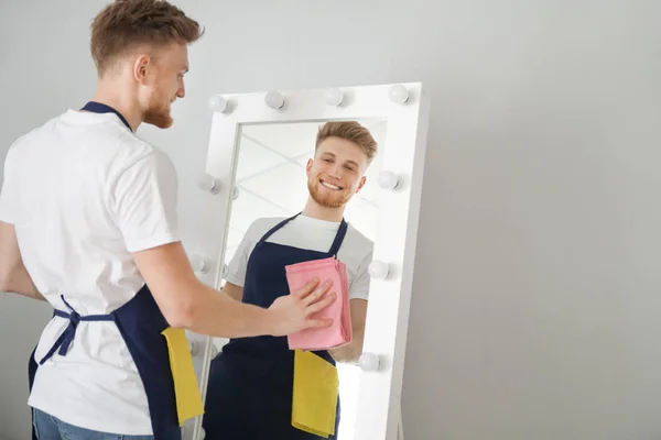 Masculino zelador limpeza espelho no quarto — Fotografia de Stock