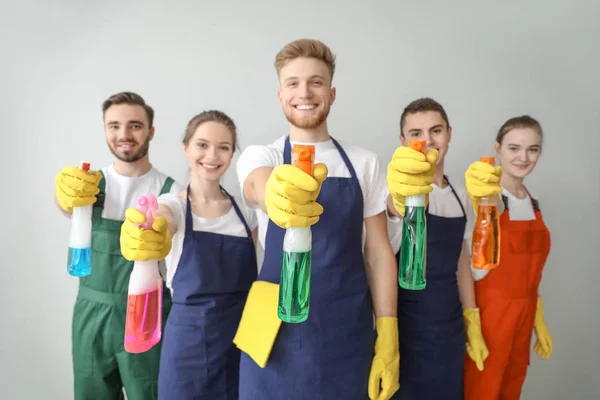 Retrato de conserjes con botellas de detergente sobre fondo claro — Foto de Stock