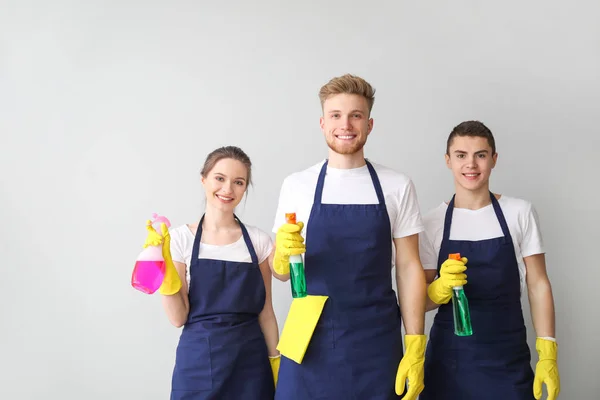 Retrato de zeladores com garrafas de detergente sobre fundo claro — Fotografia de Stock