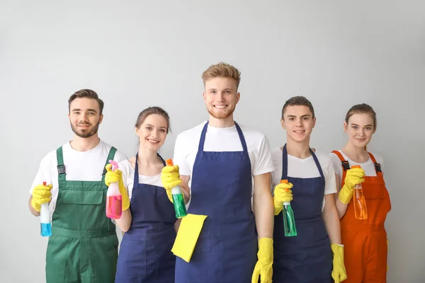 Portrait of janitors with bottles of detergent on light background — Stock Photo, Image