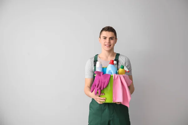 Porträt eines männlichen Hausmeisters mit Putzmitteln auf hellem Hintergrund — Stockfoto