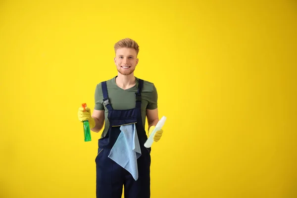 Portrait of male janitor with cleaning supplies on color background — Stock Photo, Image