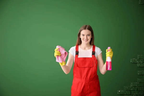 Portret van vrouwelijke conciërge met schoonmaakbenodigdheden op kleur achtergrond — Stockfoto