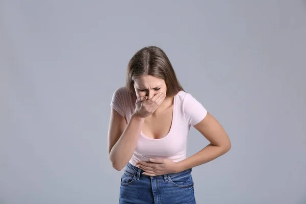 Donna incinta affetta da tossicosi su sfondo grigio — Foto Stock