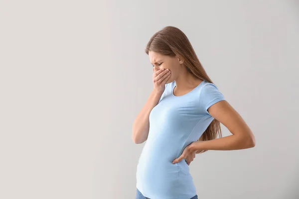 Pregnant woman suffering from toxicosis on light background — Stock Photo, Image