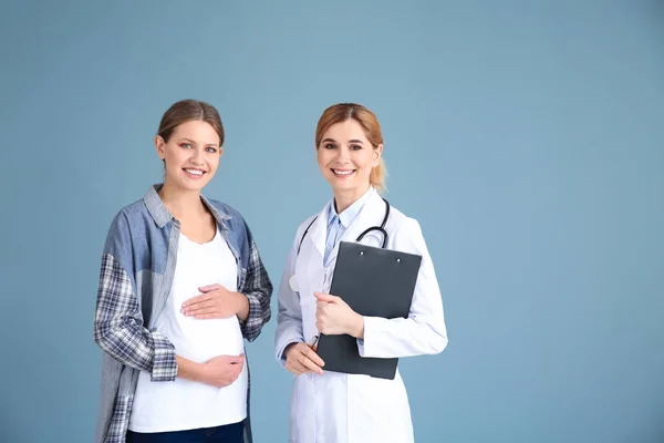 Ginecólogo con mujer embarazada joven sobre fondo gris —  Fotos de Stock