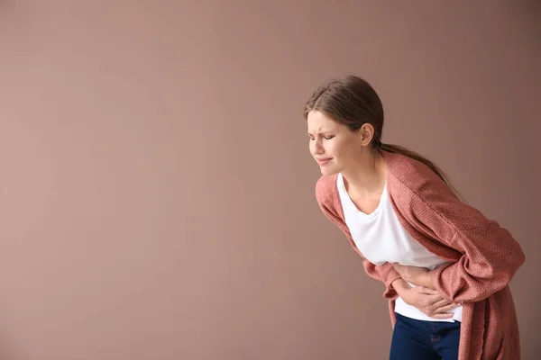 Young woman suffering from pain on color background — Stock Photo, Image