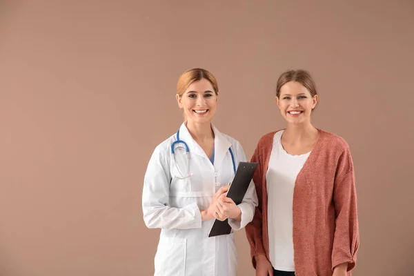 Ginekolog z pacjentem na kolorowym tle — Zdjęcie stockowe