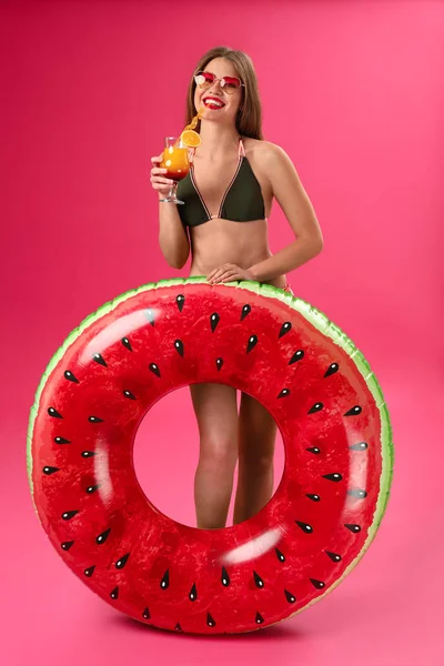 Hermosa mujer joven con anillo inflable y cóctel sobre fondo de color — Foto de Stock