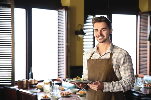 Young male waiter with salad in restaurant — Stock Photo, Image