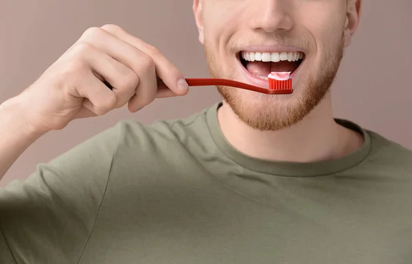 Jeune homme nettoyer les dents sur fond de couleur, gros plan — Photo