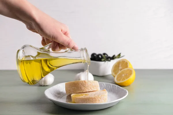 Kvinna hälla välsmakande olivolja från flaska på färskt bröd — Stockfoto