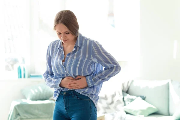 Giovane donna che soffre di mal di stomaco a casa — Foto Stock