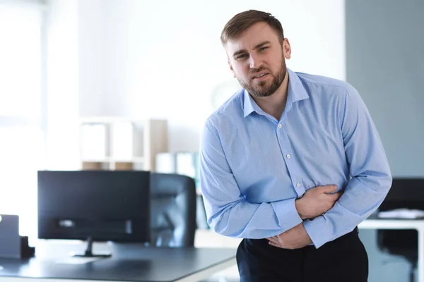 Young man suffering from stomachache in office — Stock Photo, Image