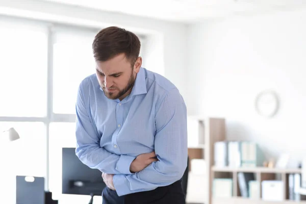 Young man suffering from stomachache in office — Stock Photo, Image