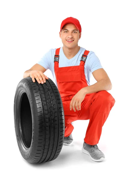 Ung manlig mekaniker i uniform med bildäck på vit bakgrund — Stockfoto
