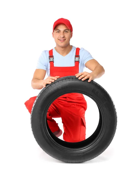 Young male mechanic in uniform with car tire on white background — ストック写真