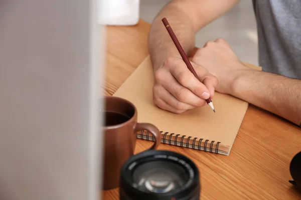 Fotógrafo escribiendo en cuaderno en la mesa —  Fotos de Stock