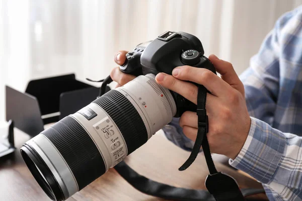 Professional photographer with modern camera at table