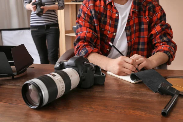 Fotógrafo profissional escrevendo em caderno à mesa — Fotografia de Stock