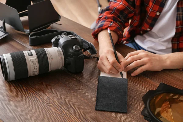Professional photographer writing in notebook at table — Stock Photo, Image