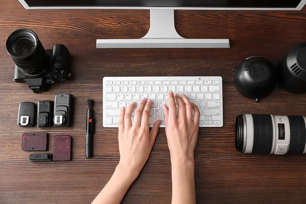 Professional photographer working on computer at table, top view