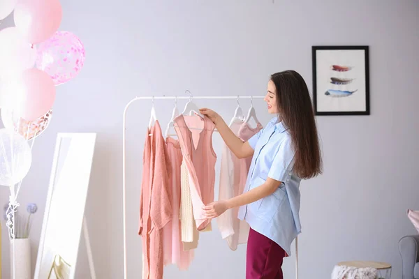 Jonge vrouw kiezen kleding in haar kleedkamer — Stockfoto