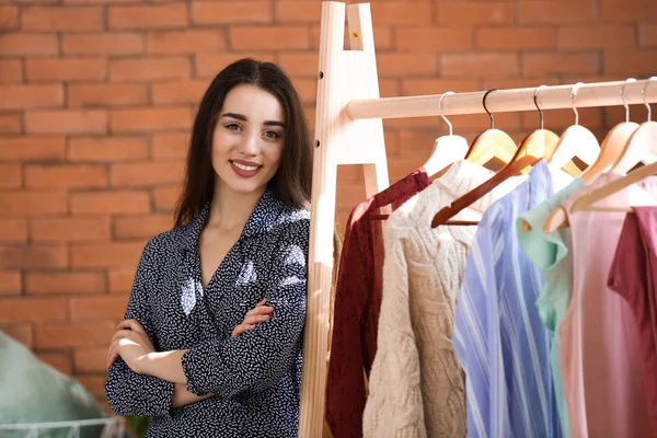 Jovem mulher de pé perto de roupas rack no camarim — Fotografia de Stock