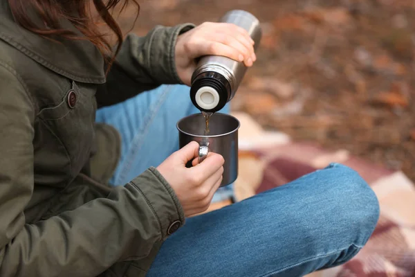 Woman drinking hot tea from thermos in forest — Stock Photo, Image